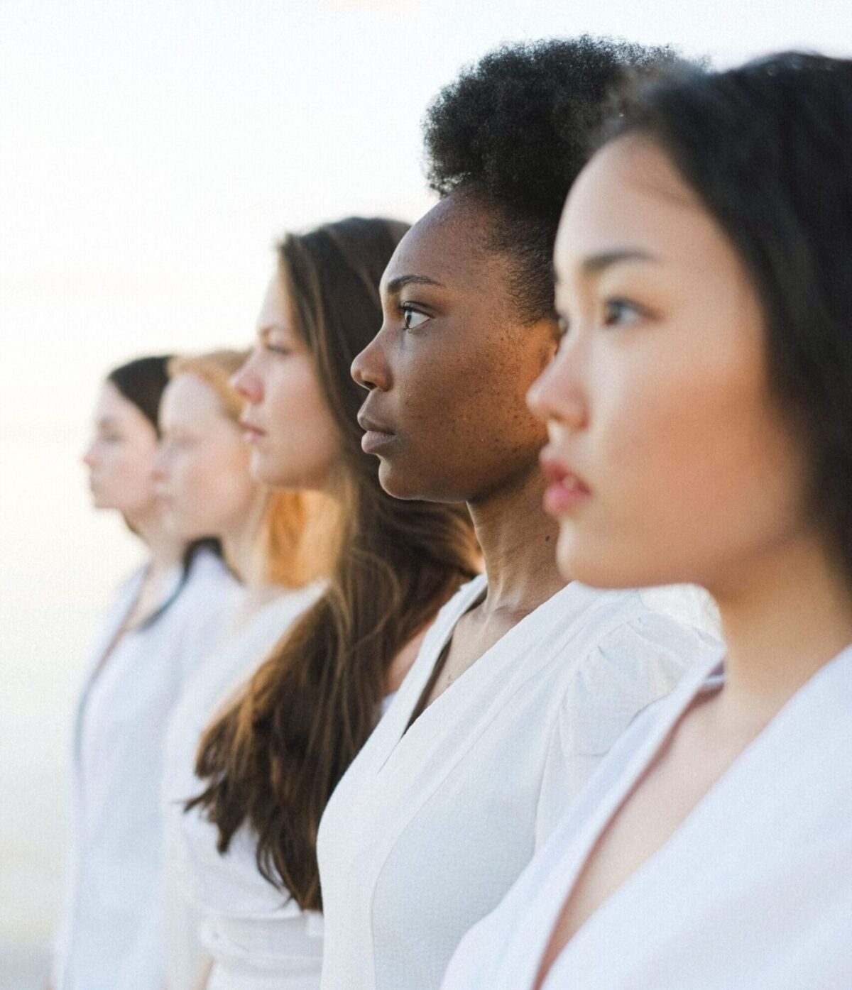 Five diverse women in white outfits standing side by side, symbolizing unity.
